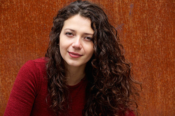 istock Beautiful young woman against brown wall 615745526