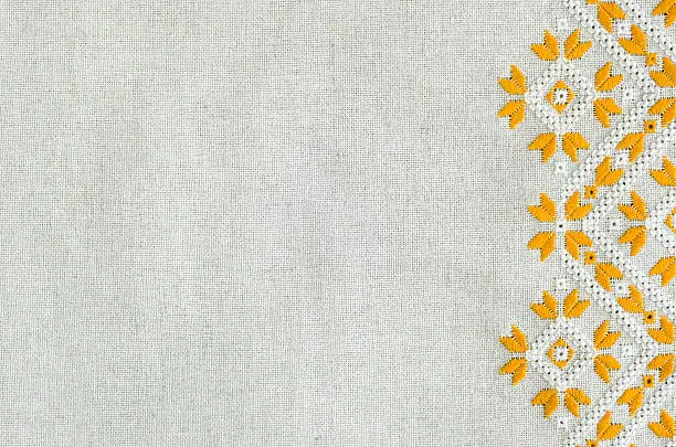 Embroidered fragment on flax by yellow and white cotton threads. Macro embroidery texture flat stitch. Geometric ornament.
