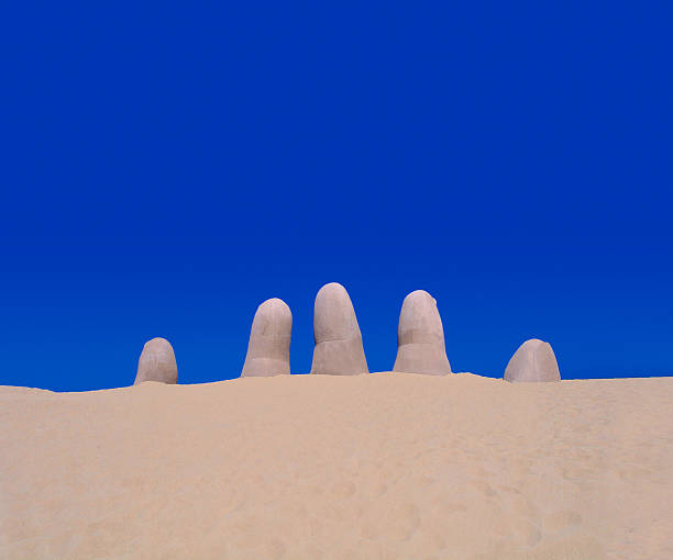 Beach Finger Sculpture at Punta del Este Beach in Uruguay Beach finger sculpture rising from the sand with a cloudless blue sky in the background. Located in Punta del Este in Uruguay. playas del este stock pictures, royalty-free photos & images