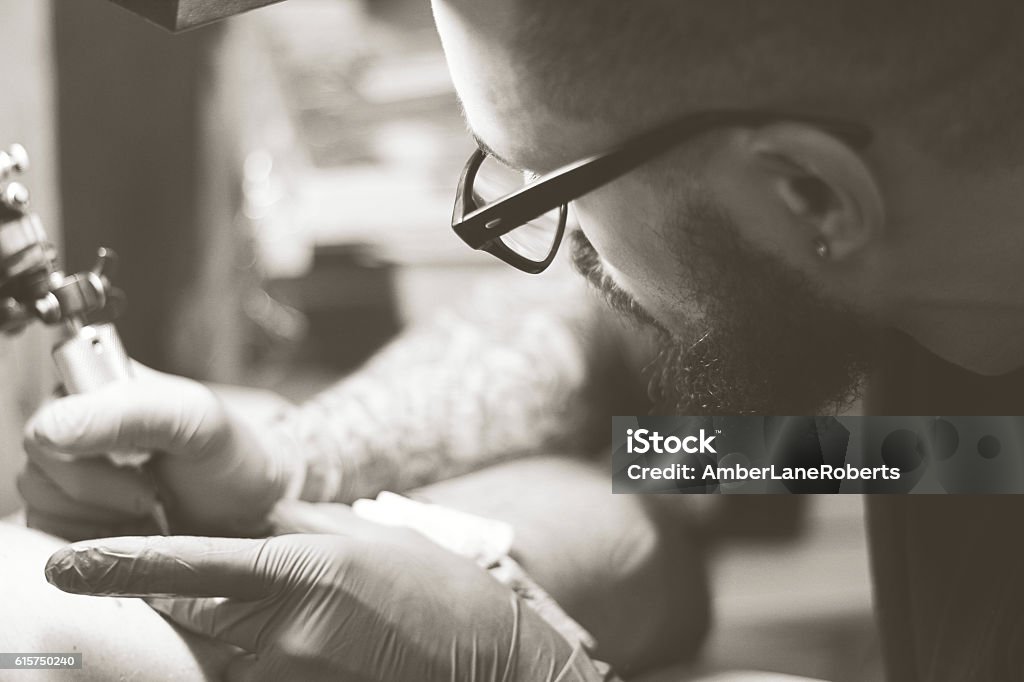 Tattoo Artist Closeup of man giving tattoo Men Stock Photo