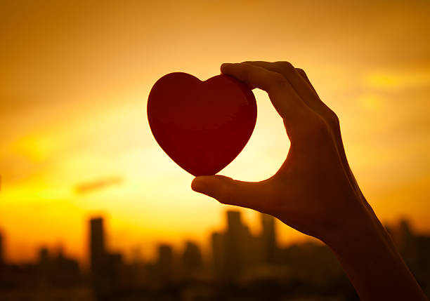 istock Hand holding heart against a city 615750304
