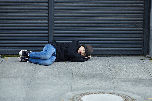 istock young homeless boy sleeping on the street 615793342