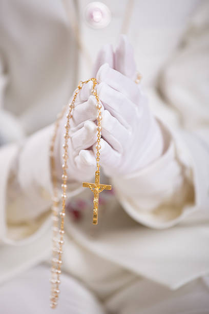 istock Hands with white gloves holding a gold rosary 615795686