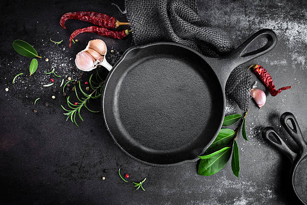 cast iron pan and spices on black metal culinary background cast iron pan and spices on black metal culinary background cooking pan overhead stock pictures, royalty-free photos & images