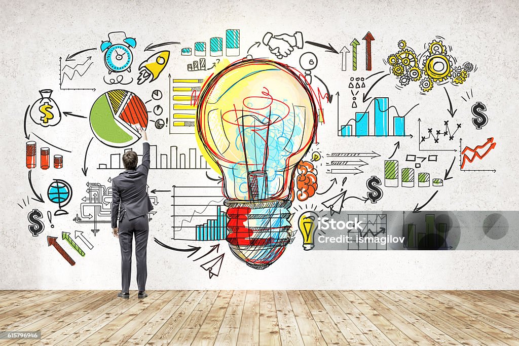 Businessman near blackboard with startup sketch Rear view of businessman in suit drawing colorful startup sketch. Large light bulb icon in center. Concept of successful startupper Market Research Stock Photo