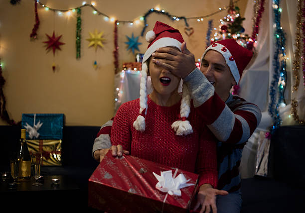 istock Man standing behind woman while giving christmas gift. 615798130
