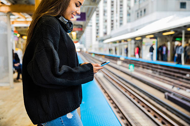 istock Young woman texting waiting subway train on platform 615803954