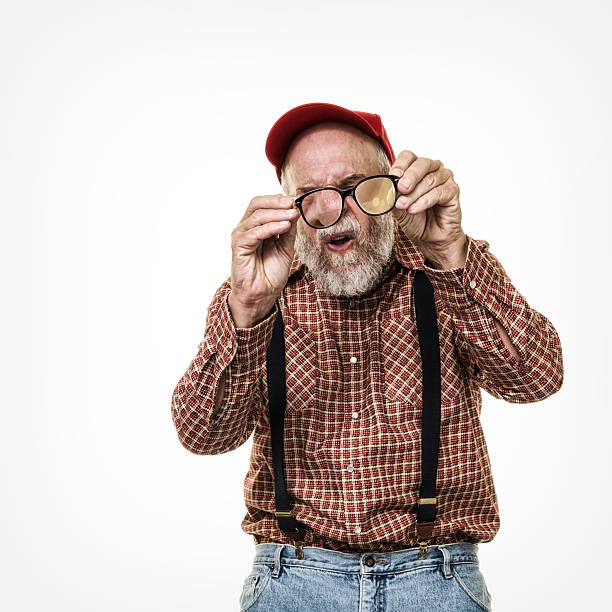 istock Squinting Redneck Red Hat Suspenders Hillbilly Man Examining Eyeglasses 615804364