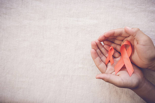 Orange Ribbons on hands on toning background, Leukemia awareness Orange Ribbons on hands on toning background, Leukemia awareness, Self Injury Awareness Day,Multiple sclerosis awareness self mutilation pictures stock pictures, royalty-free photos & images