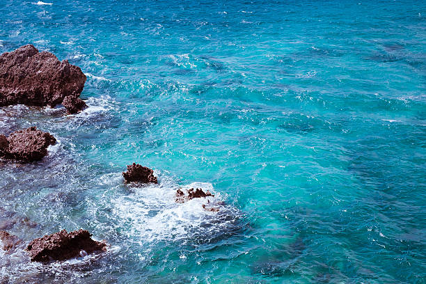 istock White waves breaking on blue sea and red rocks Okinawa 615815452