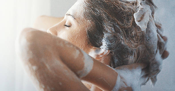 Washing hair. Closeup side view of mid 20's woman completely enjoying washiing her blond colored hair. She's going her finger through soapy hair, faced to the bathroom window. shampoo stock pictures, royalty-free photos & images