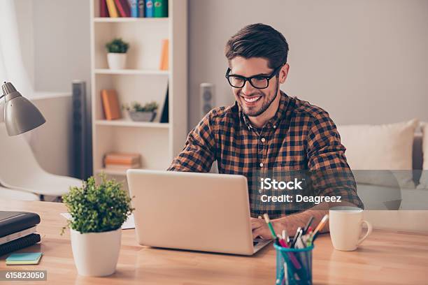 Apuesto Joven Alegre Con Gafas Escribiendo En La Computadora Portátil Foto de stock y más banco de imágenes de Ordenador portátil