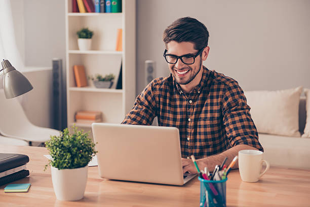 istock Handsome cheerful young man in glasses typing on laptop 615823050