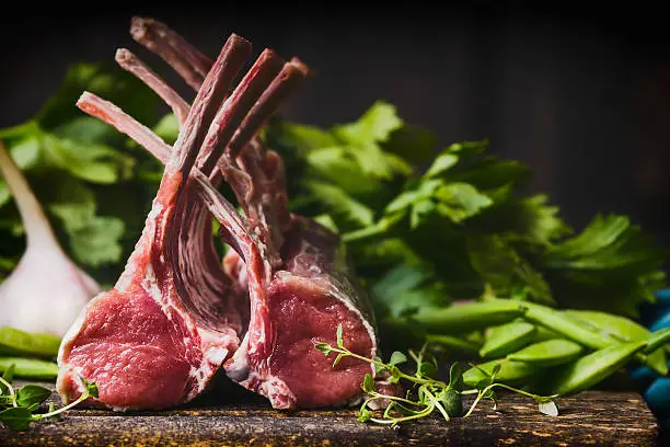 Rack of lamb , raw meat with bone on rustic kitchen table at wooden background, side view