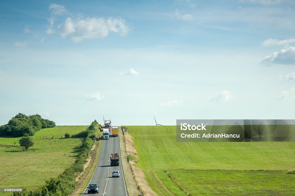 carretera con coches, camiones campos verdes y molino de viento aéreo - Foto de stock de Francia libre de derechos