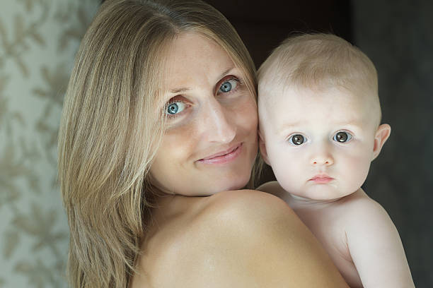 Madre feliz sosteniendo a su lindo bebé en brazos - foto de stock