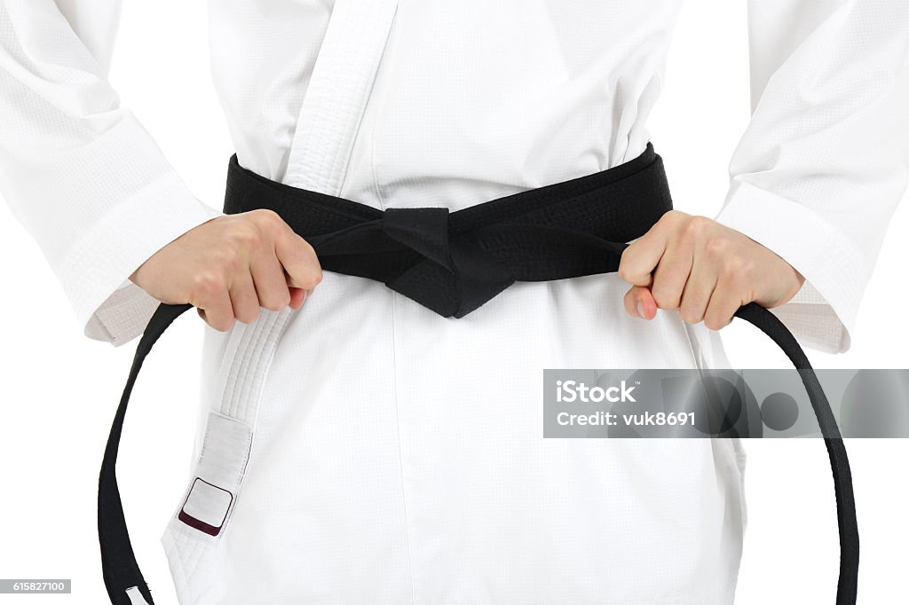 Black belt Young karate guy tying black belt, isolated on white background Jujitsu Stock Photo