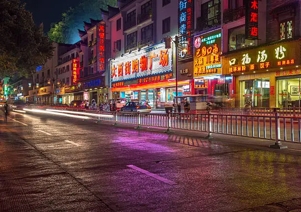 Neon reflections on the wet tarmac of Pantao road, Yangshuo, China.