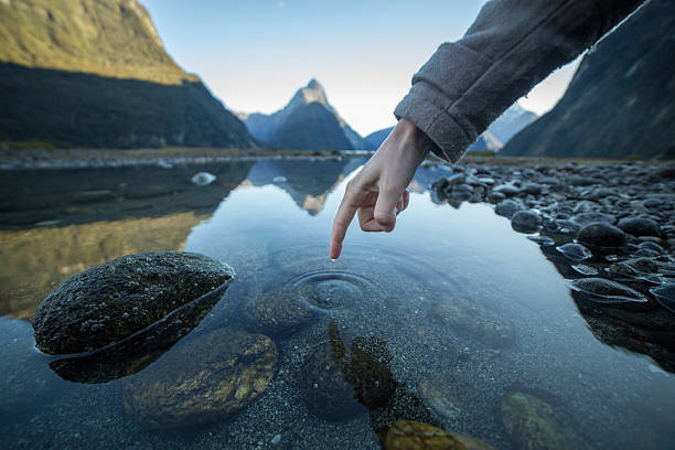 istock Finger touches surface of mountain lake 615827206