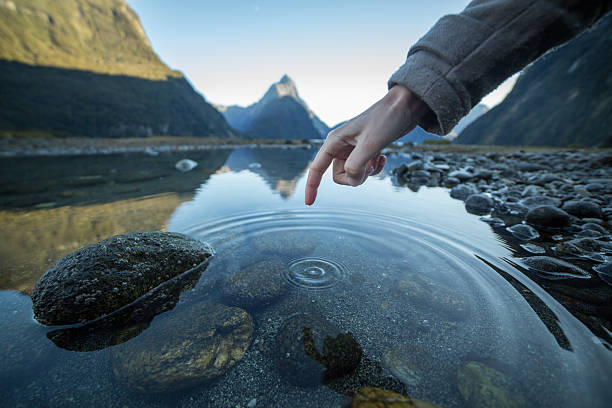 istock Finger touches surface of mountain lake 615828672