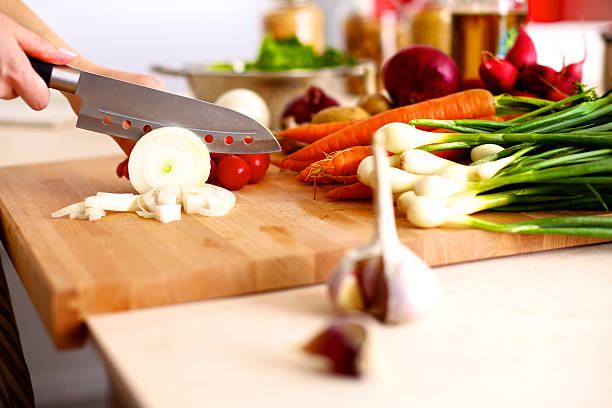 istock Young woman cutting vegetables in the kitchen 615830878