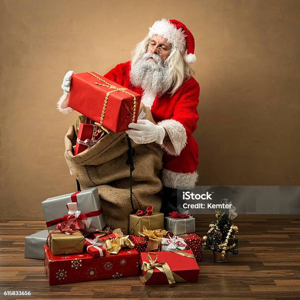 Santa Claus Looking At Present In His Hands Stock Photo - Download Image Now - Santa Claus, Gift, Bag