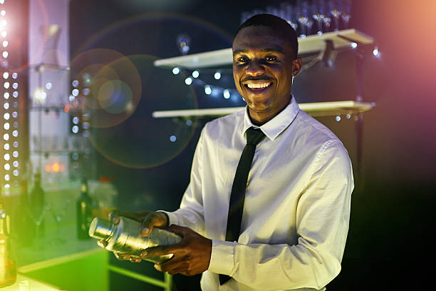 What's shaking? Portrait of a happy young barman mixing a cocktail behind his bar cocktail bar busy stock pictures, royalty-free photos & images