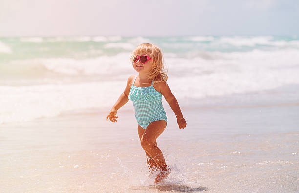 istock little girl run play with waves on the beach 615834962