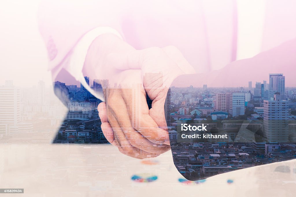 Double exposure of handshake with citi background Double exposure of handshake with citi background for investment, devlopment concept. Handshake Stock Photo