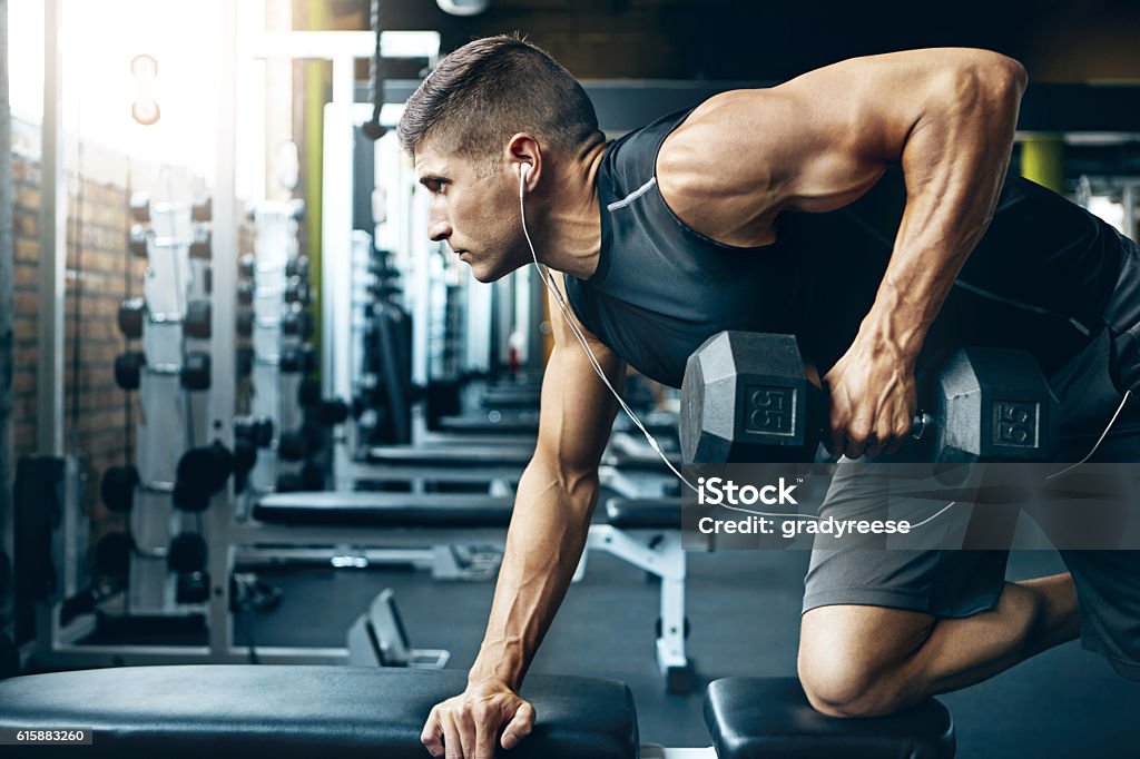 Difficult doesn’t mean impossible! Shot of a man doing weight training at the gym Gym Stock Photo