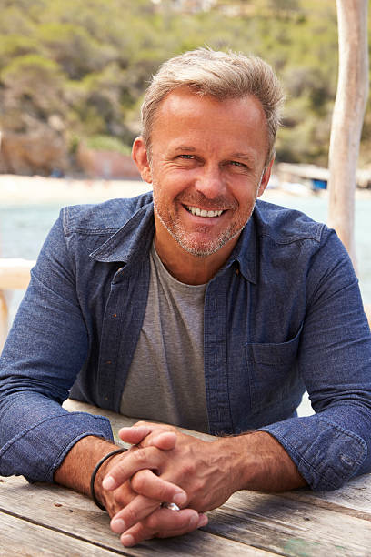 istock Middle aged Caucasian man sitting at a table on a jetty 615885160