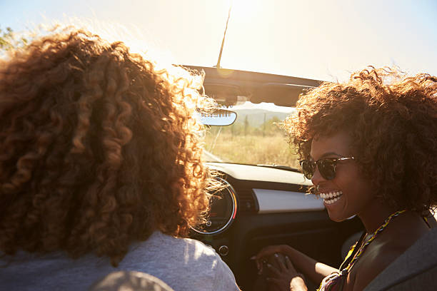 istock Couple in an open top car, rear passenger point of 615885588