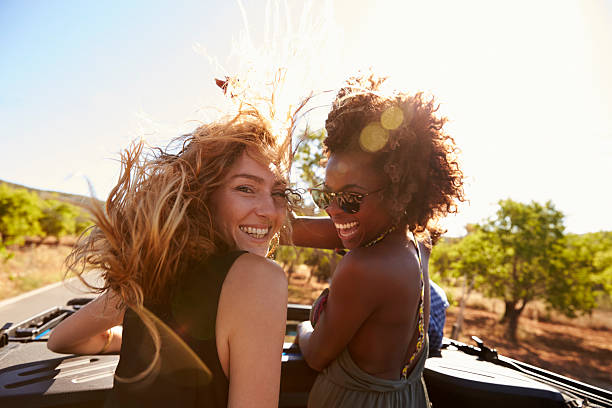 deux femmes debout à l’arrière d’une voiture ouverte qui tourne - multi ethnic group flash photos et images de collection