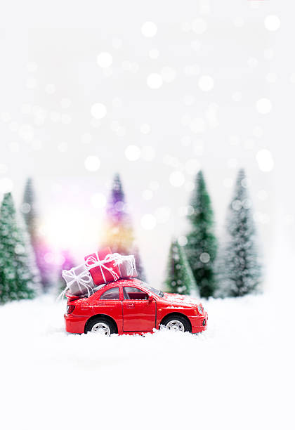 foresta invernale innevata con auto rossa che porta regali di natale - schneelandschaft foto e immagini stock