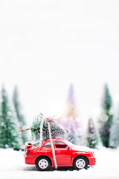 foresta invernale con auto rossa in miniatura che trasporta un albero di natale - schneelandschaft foto e immagini stock