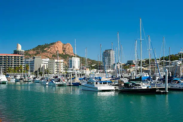 Boats moored in the tranquil water of Townsville marina, Queensland with modern high waterfront architecture behind