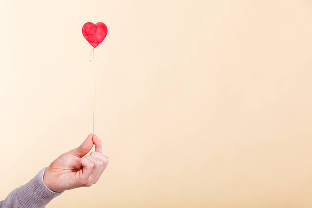 istock Male hand with little heart on stick. 615889728