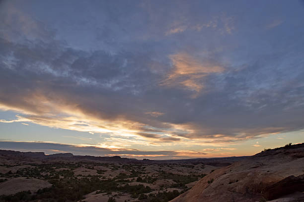 istock Desert sunset wide angle with clouds and brush and stone 615890760