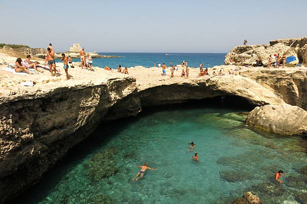 swimmers and sunbathers at Grotta della Poesia in Puglia, Italy stock photo