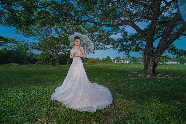 Model wearing a white wedding dress in  lawn.