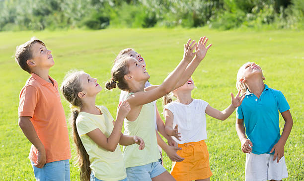 istock active kids jumping together in park on summer 615893696