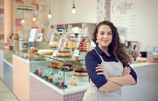 Portrait of a young woman standing inside her cake shop