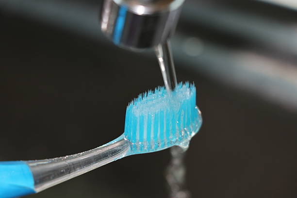 istock Toothbrush no more toothpaste near the tap sink open water 615896410