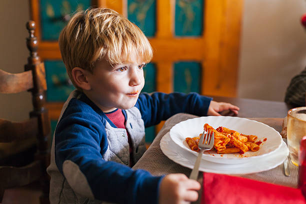 blond dziecko zjada danie z makaronu pomidorowego na boże narodzenie - penne rigatoni pasta tomato pasta zdjęcia i obrazy z banku zdjęć