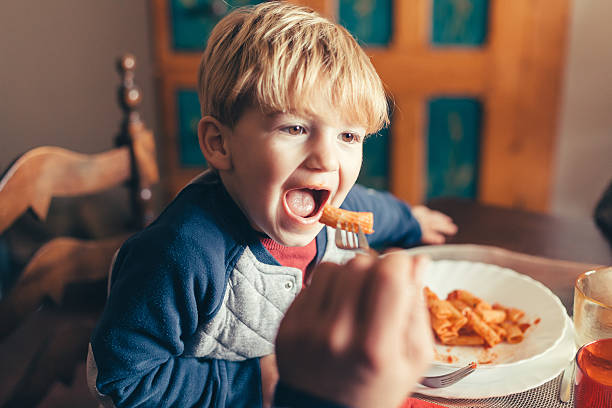 blond dziecko zjada danie z makaronu pomidorowego na boże narodzenie - penne rigatoni pasta tomato pasta zdjęcia i obrazy z banku zdjęć