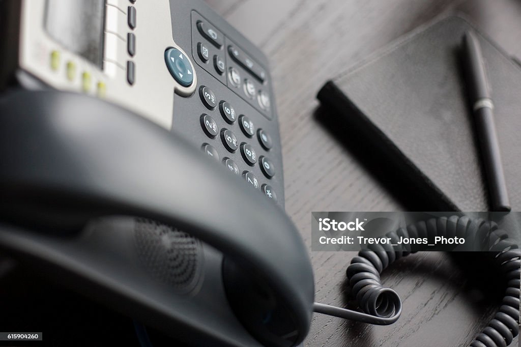 Phone sitting on a desk in the office Office contact phone number.  Telephone Number Stock Photo