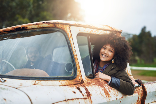 Shot of a happy young woman sitting in a rusty old truck