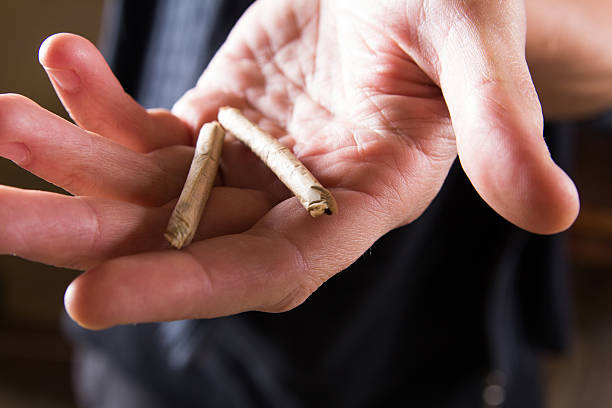 istock Marijuana joints in the mans hand. Man offering drugs 615907472