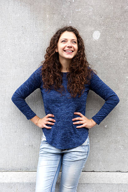 istock Confident young woman standing against gray wall 615908832