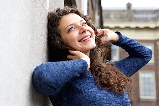 istock Relaxing young woman leaning to a wall outdoors and smiling 615913018